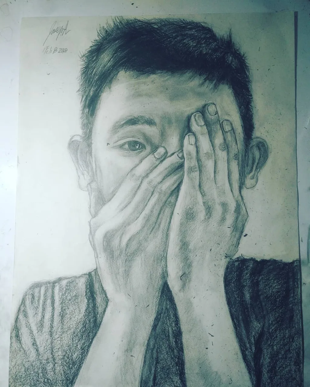 Graphite portrait of a young man covering his face with his hands