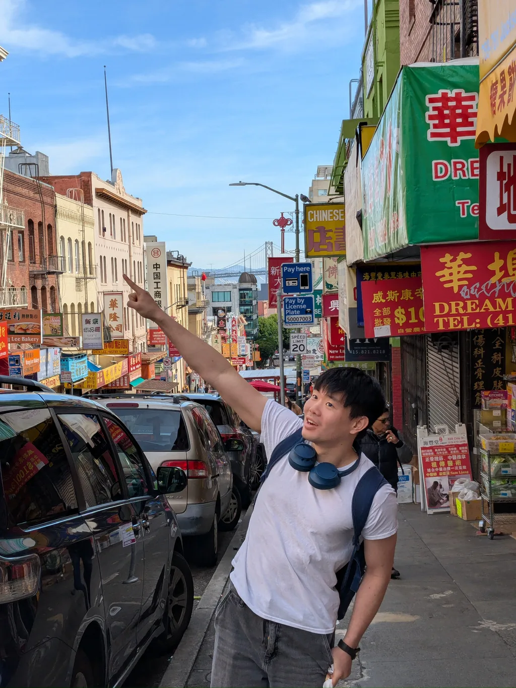 Joseph Liao pointing at shop signs in San Francisco Chinatown