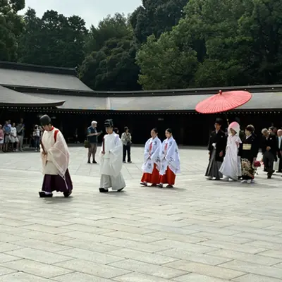 Shinto wedding procession with a red umbrella at a shrine courtyard