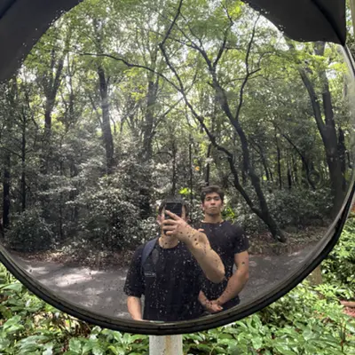 Two friends reflected in a convex mirror in a forest