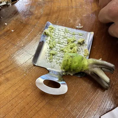 Fresh wasabi root being grated on a metal grater
