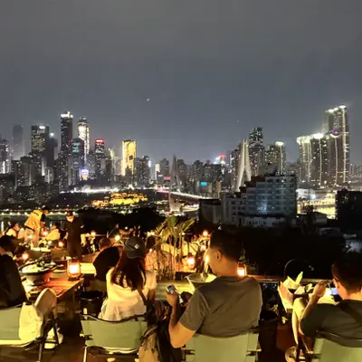 Rooftop diners overlooking a city skyline at night