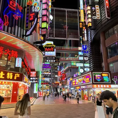 Neon-lit pedestrian street at night lined with shops
