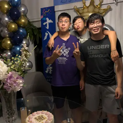 Three friends posing at a birthday party with balloons and a crown