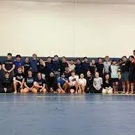 Large group of wrestlers posing on a gym mat