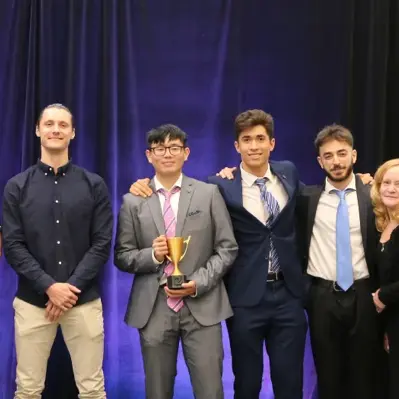 Group in suits on stage holding a gold trophy