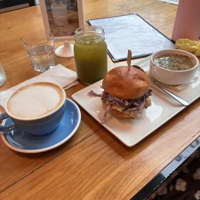 Burger, latte, soup, and green juice on a cafe table