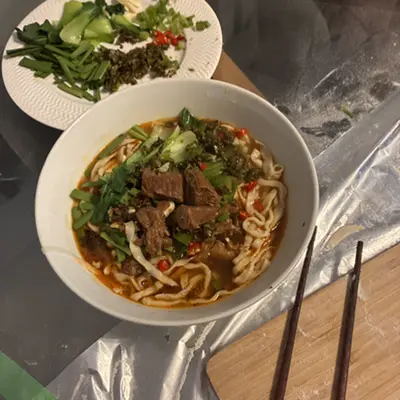 Bowl of beef noodles in chili broth with greens