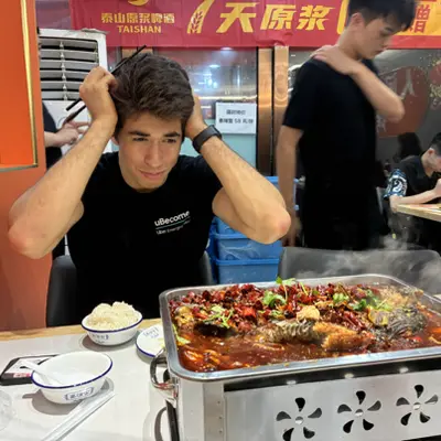 Friend reacting dramatically beside a large tray of spicy grilled fish