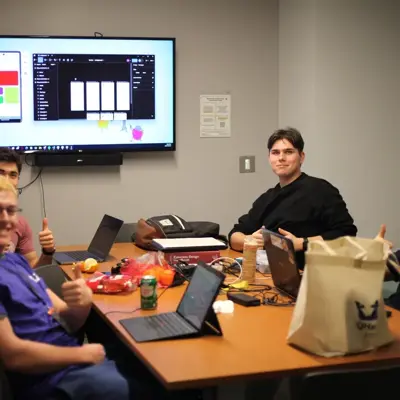 Team working on laptops around a table at a hackathon